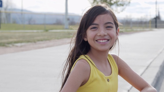 一个可爱的10-11岁西班牙裔，拉丁，波利尼西亚小女孩微笑着看她的肩膀在春天或夏天的户外视频下载