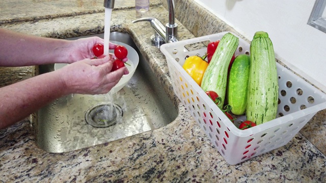 特写的手，洗蔬菜(西红柿)在家庭厨房水槽视频下载