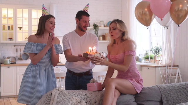 年轻美女吹灭生日蛋糕上的蜡烛的生日派对视频素材