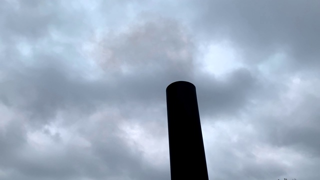 在灰色多云的天空的衬托下，黑色的工厂烟囱冒出了烟。木材加热产生的烟。大气污染。环境问题。视频下载
