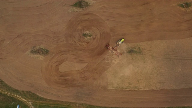 用无人机射击。拖拉机在犁地，画了一个圈。准备播种。从上往下看。4 k视频素材