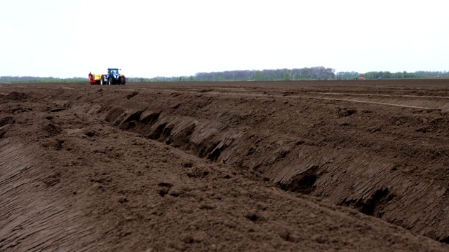 近距离观察，农田里的棕色土壤。附近，拖拉机在工作，耕地，种植土豆。农业种植马铃薯。现代农业。生态农场。春天视频素材