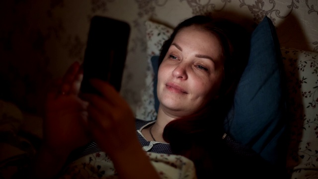 交流的概念，一个女人晚上躺在床上，通过视频和朋友在线聊天进行交流视频下载