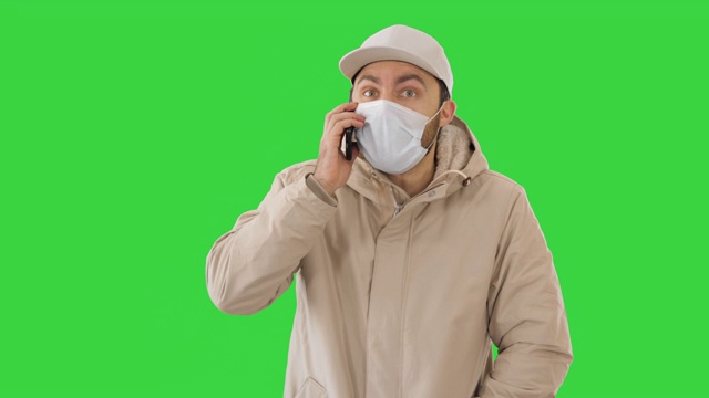 一名欧洲年轻人在绿屏上戴着医用口罩打电话视频素材