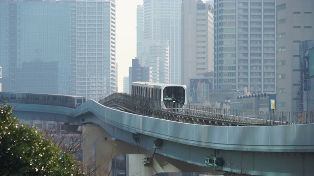 2018年1月18日，日本东京港区盐堂区，“Yurikamome”(东京滨水新干线滨水线)在高层办公楼和住宅楼之间的高架铁路上运行。视频下载