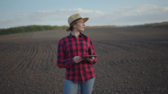 身穿红色格子衬衫、头戴帽子的农妇手里拿着一块平板电脑，正在进行经济计算视频素材