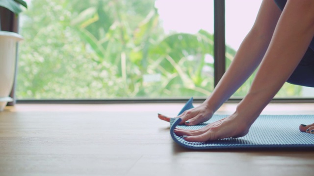 女人铺开瑜伽垫，准备在瑜伽冥想训练视频下载