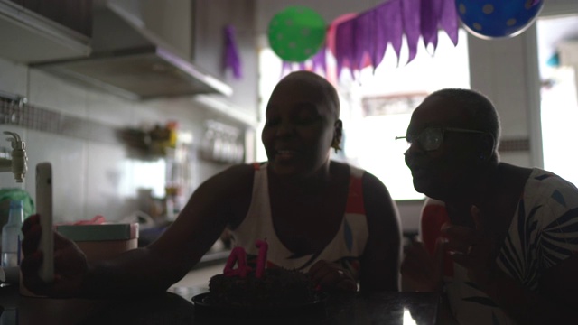 母亲和女儿做一个视频电话在生日距离派对上的移动电话视频素材