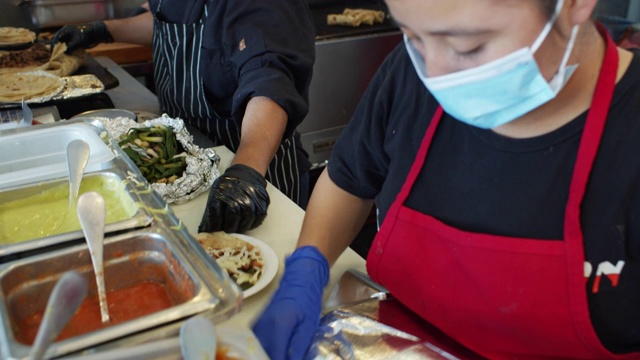 新冠肺炎疫情封锁期间，餐厅里的厨师戴着口罩和手套制作墨西哥玉米卷视频素材
