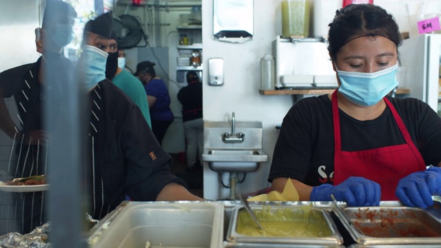 2019冠状病毒肺炎一级防范禁闭期间，厨师戴着口罩和手套在厨房工作视频素材
