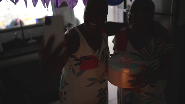 母亲和女儿做一个视频电话在生日距离派对上的移动电话视频素材