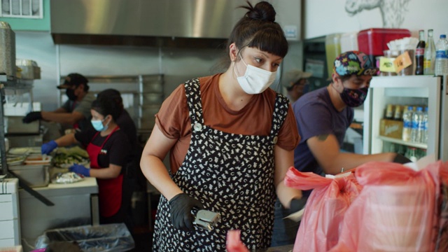 2019冠状病毒肺炎封锁期间戴口罩和手套的餐厅员工在工作时组装外卖和外卖订单视频素材