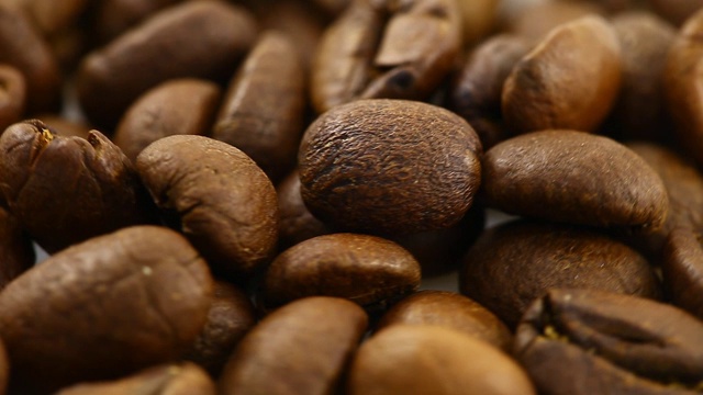 棕色烘焙的咖啡豆旋转着，慢慢地旋转着，俯视图，特写。视频素材