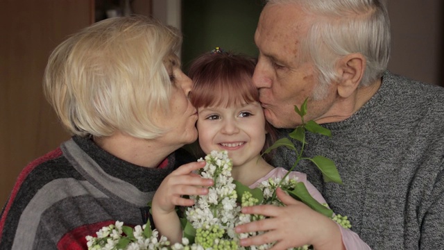 爷爷和奶奶在家里亲吻他们的小孙女的头视频下载