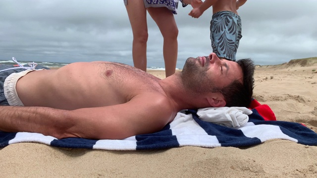 在海滩上晒太阳的人。英俊的男人晒日光浴，休息，放松在海边视频素材