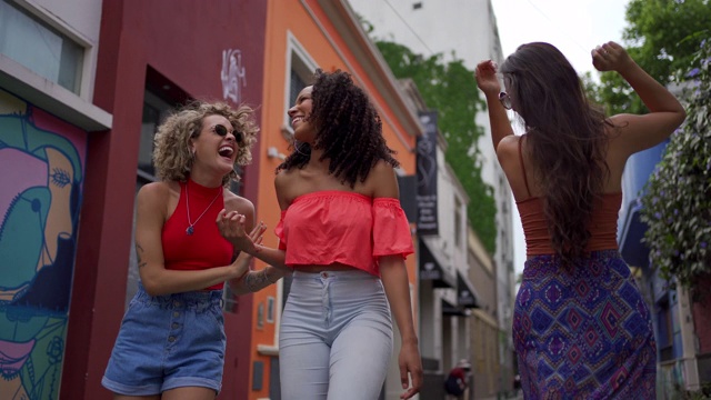 阳光明媚的日子里，欢快的妇女们一边跳舞一边走在街上视频下载