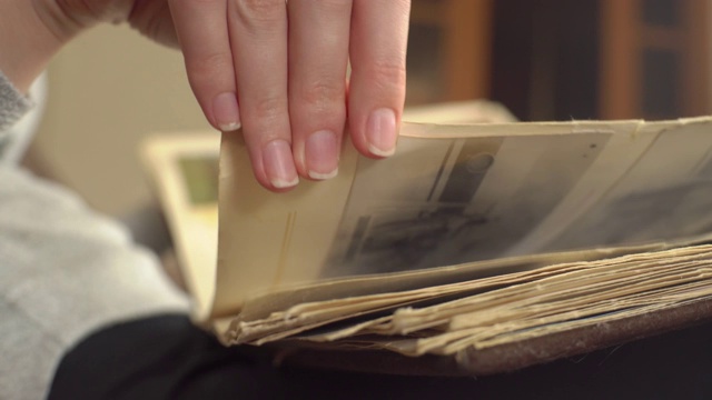 一个女人正在家里看旧相册。女人回忆过去，一如既往。视频下载