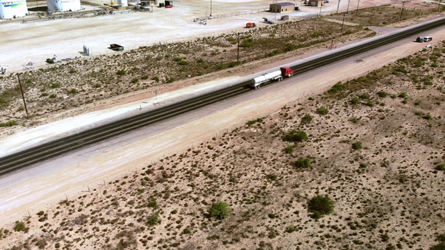 无人机拍摄的德克萨斯州西部石油和天然气水力压裂国家的一条双车道高速公路，上面有工业车辆和半卡车视频下载