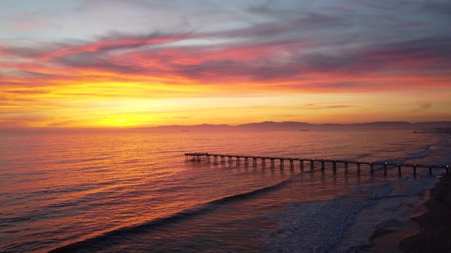 无人机俯瞰加利福尼亚码头、海洋和空旷海滩的日落。——延时视频下载