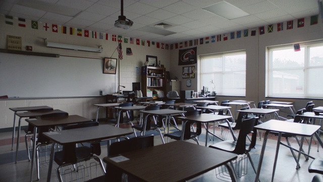 一间空教室里摆满了空课桌。视频素材