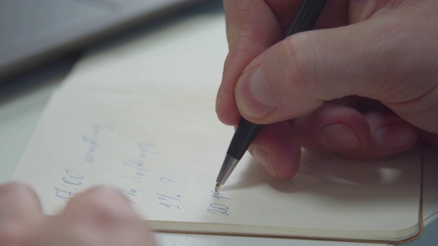 一个男人用钢笔在笔记本上写字。特写镜头视频素材