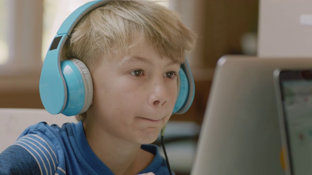 加州大学的小男孩戴上耳机，开始在笔记本电脑上打字。视频下载