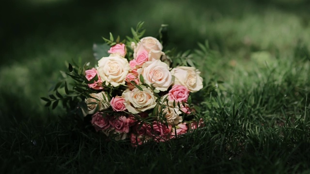 草地上放着一束牡丹和玫瑰。美丽优雅的新娘花束。一束粉红色和白色的花。婚礼的细节。视频素材