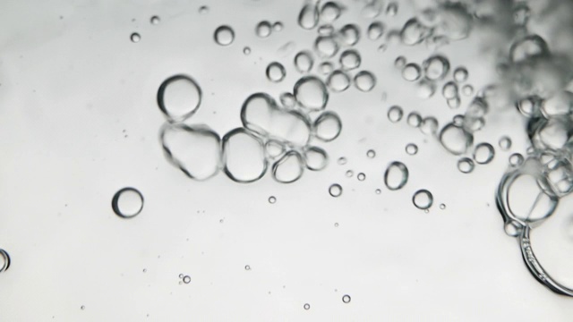 往玻璃杯里倒水时，水里有气泡，照片来自水下角落。创意抽象背景，银色调风格。视频素材