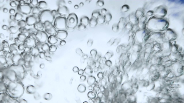 往玻璃杯里倒水时，水里有气泡，照片来自水下角落。创意抽象背景，银色调风格。视频素材
