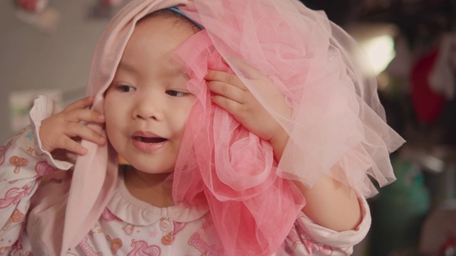 慢镜头特写快乐的亚洲女孩玩打扮成一个公主用粉红色的裙子。视频下载