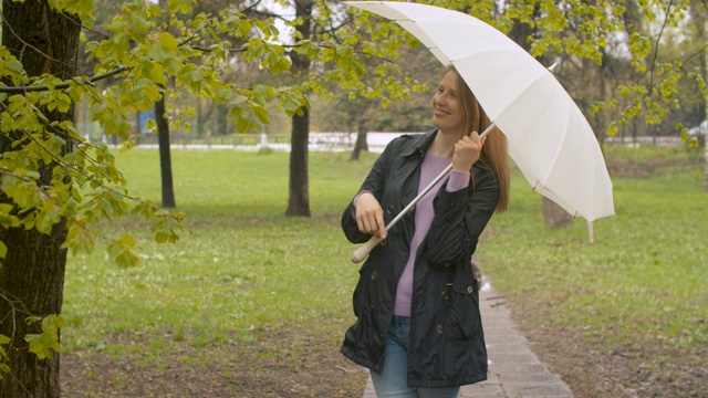 在公园里撑着伞的快乐女人视频素材