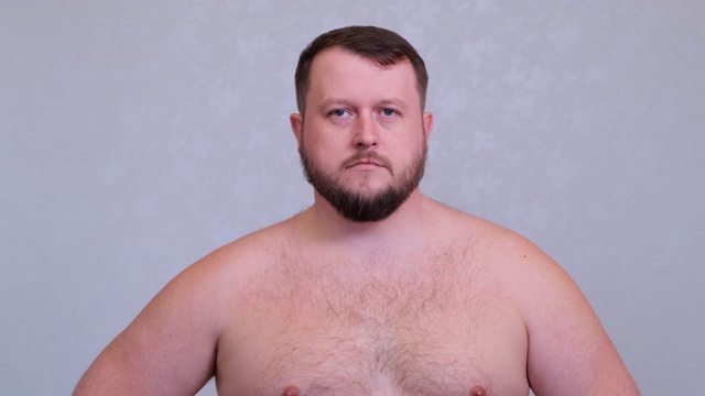 灰色背景上的一幅胖胡子赤裸上身的男子肖像视频下载