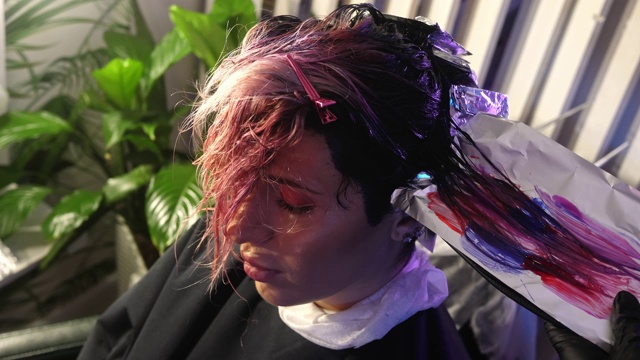 发型师将客户的头发染成粉紫色渐变。视频下载