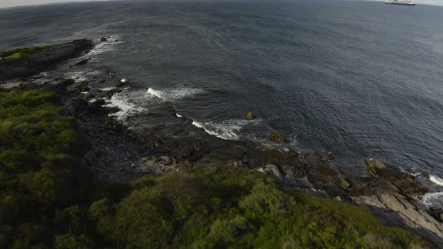 从岩石嶙峋的海岸线向海上移动的渡轮倾斜视频下载