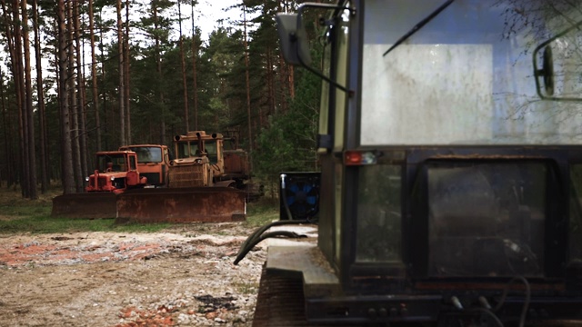 三辆生锈的废弃履带式拖拉机，后面是装有大玻璃窗的机器视频素材