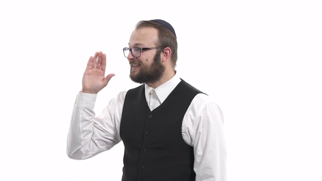 有吸引力的友好的看起来年轻的犹太男子快乐地微笑，说你好，嗨，挥手。打招呼的方式。孤立，在白色背景上视频下载