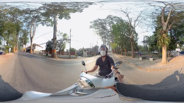 一名男子戴着n95面具骑着摩托车行驶在清迈的道路上视频素材