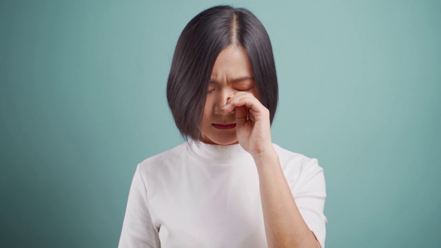 亚洲女人悲伤和哭泣站在孤立的蓝色背景。4 k的视频。情感的民主观。视频素材