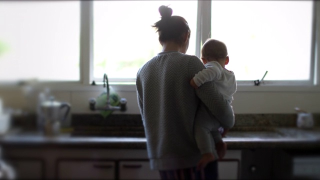 母亲抱着婴儿在厨房多任务视频素材