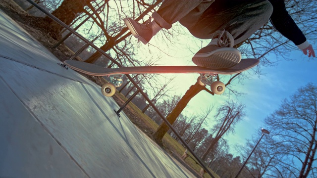 SLO MO女滑板者跳跃和降落在她的滑板在一个阳光灿烂的滑板公园视频下载
