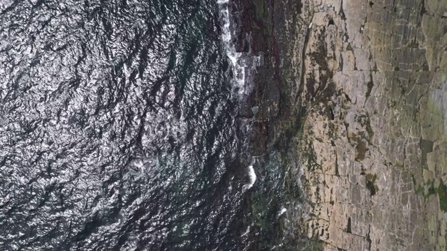 海浪冲击多岩石的海岸线的下降镜头视频下载