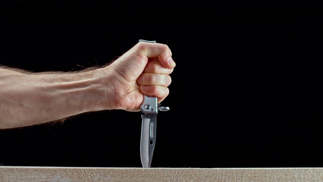 SLO MO LD男性的手拿着一把刀，将它刺进木头里视频下载