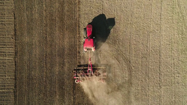 空中俯视图拖拉机在田间工作与现代播种机在一个新犁的土地。播种机械化。视频下载