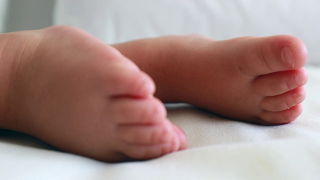 婴儿的脚和脚趾近距离睡觉。一个一岁的蹒跚学步的婴儿两个得到特写镜头视频素材