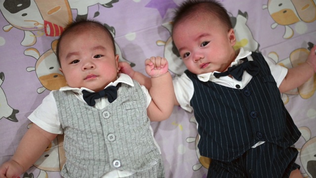 一对5个月大的亚洲华人双胞胎男婴躺在床上寻求父母的关注视频素材