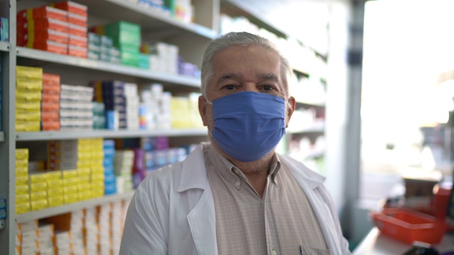 男性年长药剂师戴着口罩在药房的肖像视频下载