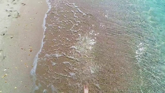 沿着海岸线走，拍海腿上的浪花视频素材