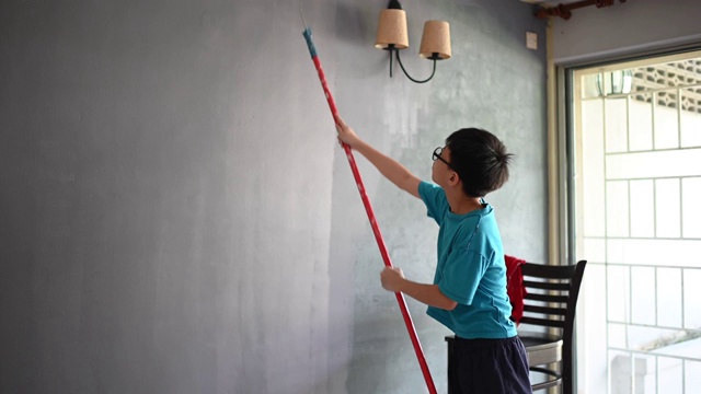 亚洲华人家庭成员的儿子粉刷房子，儿子帮助他的父亲视频素材