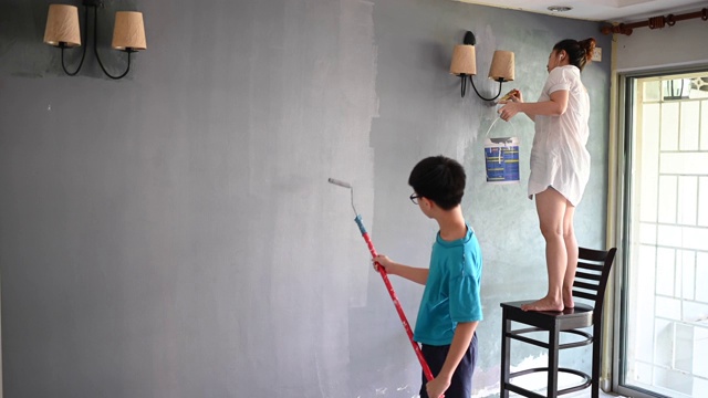 亚裔华人家庭成员在粉刷房子，儿子在帮妈妈视频素材