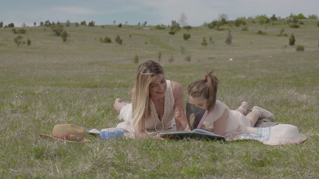 快乐的年轻的母亲和女儿在公园有乐趣阅读一本书s LOG2视频下载